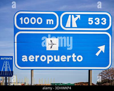 Segnaletica stradale che dirige il traffico verso l'aeroporto di Siviglia, situato a circa 1000 metri di distanza. I cartelli informativi blu forniscono la navigazione. Foto Stock