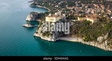 Vista panoramica aerea del Castello di Duino su alte scogliere calcaree con mare Adriatico e villaggio costiero Friuli Venezia Giulia Italia Foto Stock