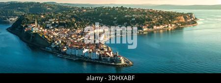 Panorama della città vecchia di Pirano e del faro su Capo Madona al tramonto dell'ora d'oro con la costa dell'Adriatico slovena Foto Stock