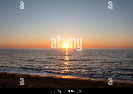 Veduta aerea del Sole che arriva sull'orizzonte e sull'Oceano Atlantico a Virginia Beach Empty Beach Foto Stock
