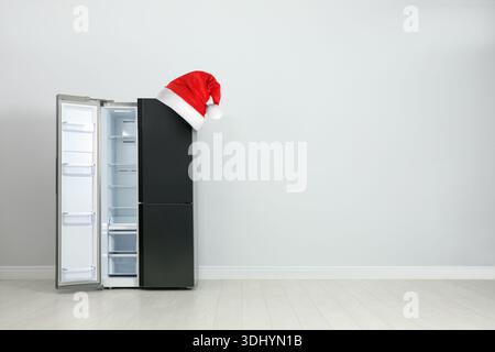 Frigorifero con cappello di Babbo Natale rosso in camera. Spazio per il testo Foto Stock