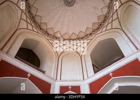 Delhi, India - 30 marzo 2024: L'immagine mostra il soffitto interno con motivi geometrici e la sezione superiore degli archi della tomba di Humayun, con intonaci rossi e bianchi e dettagli architettonici. Foto Stock