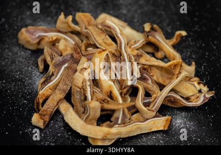 orecchie di maiale essiccate o fritte, un tipo di spuntino o un regalo per cani. Possono essere preparati come prelibatezza umana in varie cucine o come cane naturale ricco di proteine Foto Stock