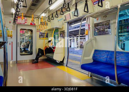 Tokyo, Giappone - 2 gennaio 2016. Interni della moderna metropolitana di Tokyo in Giappone, sedili puliti e corrimano con i passeggeri che utilizzano smartphone. Foto Stock