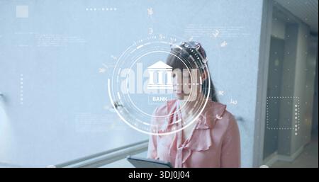 Con una compressa, donna di mezza età che studia HUD in un corridoio blu pallido con ringhiera, in camicetta rosa Foto Stock