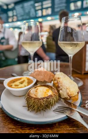 Piatto gourmet di tapas con Urchin di mare al forno e vino bianco Foto Stock