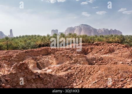 Resti e rovine dell'antica città di Dadan in Arabia Saudita con palme e montagne rocciose sullo sfondo che evidenziano il deserto archeologico Foto Stock