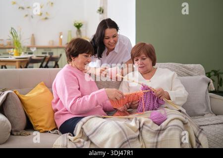 importanza del legame femminile nelle famiglie. L'arte durevole della maglieria: L'antica arte della maglieria colma il divario di età tra i giovani e gli anziani. Foto Stock