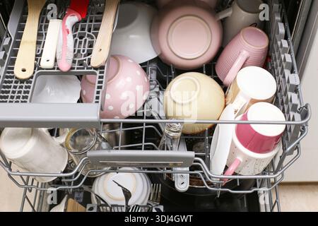 Lavare i piatti in lavastoviglie. Piatti tazze e posate organizzate in rack. Moderno apparecchio da cucina per l'uso quotidiano. Sfondo delle faccende domestiche. Foto Stock