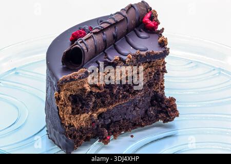 Squisito dessert con glassa di cioccolato, arredamento e frutti di bosco. Primo piano di una fetta di torta che mostra strati di delicata spugna e panna. Foto Stock