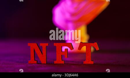 Lettere NFT rosse con effetto fumo al neon viola rosa arancio e sfondo scuro Foto Stock