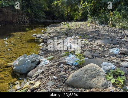 Pampanga, Filippine. 25 gennaio 2026. Un sacchetto di pannolini usati giace in un letto di fiume essiccato dopo essere stato scaricato nel fiume. Quando il livello dell'acqua scese durante la stagione secca, la borsa si depositò sul letto del fiume e il suo contenuto fu sparso tra le pietre da animali selvatici. Tali pratiche informali di dumping persistono nelle regioni rurali, con alcuni residenti che ipotizzano che le piogge stagionali laveranno i residui a valle. Le Filippine sono tra i maggiori contributori al mondo all'inquinamento marino da plastica e rifiuti, con fiumi che fungono da vie principali che trasportano detriti nell'oceano.credito: Kevin Izorce/Alamy Live News Foto Stock