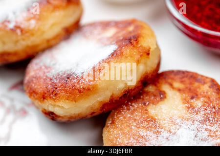 Primo piano di tre sciroppi dorati, una popolare colazione dell'Europa orientale o un piatto da dessert a base di quark/formaggio fresco, abbondantemente cosparso di Foto Stock