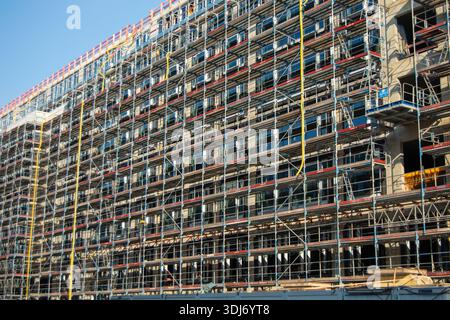 Un grande cantiere caratterizzato da un edificio in fase di ristrutturazione, con impalcature e numerose finestre Foto Stock