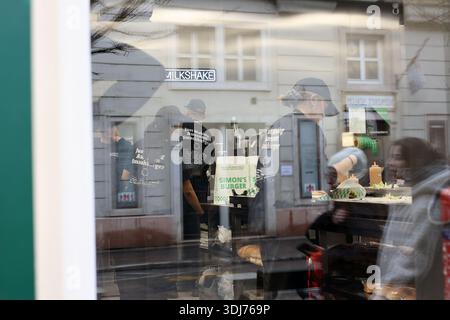 Clienti e personale all'interno del ristorante Simon's Burger's della catena di fast-food ungherese attraverso la vetrina di Budapest, Ungheria Foto Stock