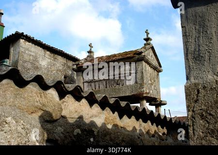 Un edificio con un tetto e una croce in cima. Il tetto è fatto di piastrelle. L'edificio è vecchio e ha un muro di pietra Foto Stock