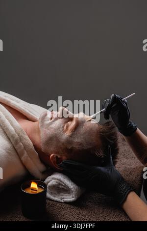 Maschera professionale ringiovanente e idratante per gli uomini alla spa, idratazione profonda e rilassamento per una pelle sana e luminosa. Foto Stock