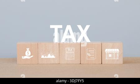 Un uomo d'affari indica un blocco di legno quadrato con un segno di percentuale e la parola tax scritta sopra. Foto Stock