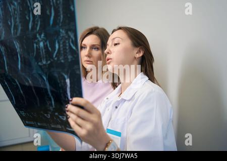 Medico donna che spiega i risultati dei raggi X al paziente. Medico e paziente, radiografia, radiologia Foto Stock