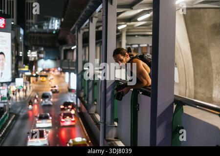 Fotografo che fotografa il traffico notturno della città Foto Stock