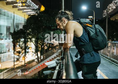 Uomo che usa lo smartphone in strada di notte Foto Stock