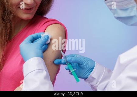 Mano di una giovane infermiera, medico che dà siringa con vaccino, inietta al paziente nel braccio. Vaccinazione, immunizzazione o prevenzione delle malattie ag Foto Stock