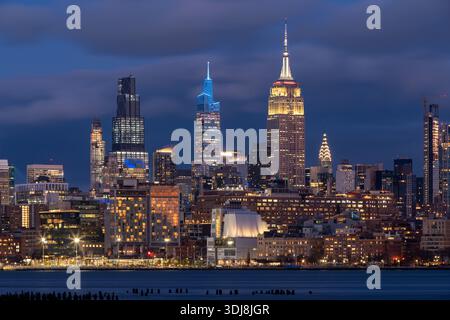 Skyline di New York City Manhattan al crepuscolo con grattacieli (Empire State Building, One Vanderbilt, JPMorgan Chase) visti dall'altra parte del fiume Hudson Foto Stock