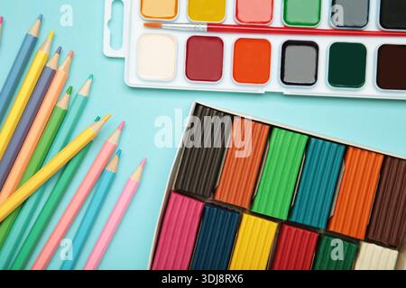 Matite colorate, plasticine e vernici ad acquerello su sfondo blu. Vista dall'alto Foto Stock