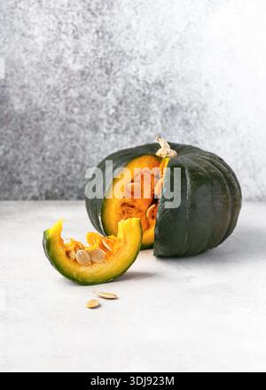 Cimella 'Zaphito' (Cucurbita maxima) squash, intero e tagliato su sfondo chiaro. Pelle verde intenso, strisce chiare e polpa gialla e arancione ricca. Foto Stock