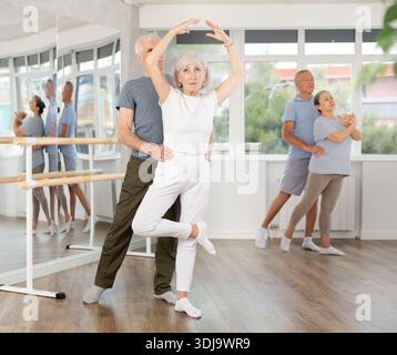 Felice coppia di ballerini maturi che eseguono coreografie con supporto durante i corsi di formazione di gruppo in studio di danza Foto Stock