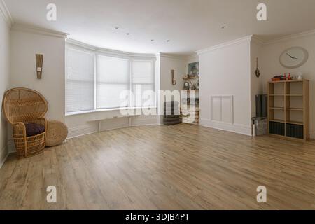 Studio yoga vuoto, spazioso e luminoso, con pavimenti in legno duro, grandi finestre bovindo e oggetti di meditazione ben organizzati. Foto Stock
