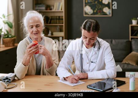 Donna caucasica anziana consulente donna donna Dottore scrittura prescrizione alla scrivania Foto Stock