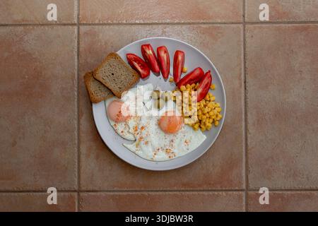 Uova fritte con verdure, pane, olive e cozze sul piatto bianco vista dall'alto Foto Stock