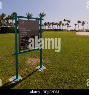Un'immagine vibrante catturata a Hawana Salalah, Oman, con un cartello pubblicitario con cornice turchese su un prato verde ben tenuto. Il sig Foto Stock