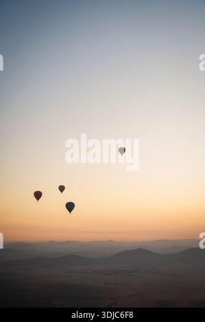 Alla deriva delle mongolfiere sulle tranquille colline all'alba vicino a Marrakech Foto Stock