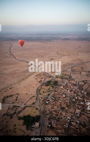 Mongolfiera rossa che galleggia sopra il villaggio del deserto vicino a Marrakech Foto Stock