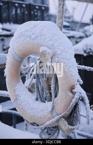 Primo piano di un salvagente coperto di neve appeso a ringhiere metalliche, Murmansk, Oblast' di Murmansk, Russia Foto Stock