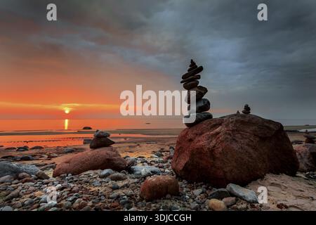 Una pila di pietre su una spiaggia sabbiosa sul Mar Baltico al tramonto, Lituania Foto Stock