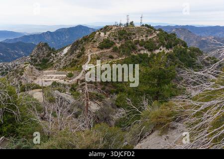 Il suggestivo e aspro paesaggio del San Gabriel Peak, caratterizzato da torri di comunicazione, un eliporto e alberi morti storditi in primo piano roccioso. Califor Foto Stock