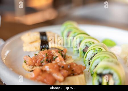 Un piatto di sushi con vari panini e guarnizioni. Il sushi include pesce fresco, avocado e riso, servito con wasabi e zenzero. Foto Stock