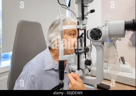 Donna anziana sottoposta a esame oculistico con lampada a fessura per un controllo visivo chiaro condotto da una donna optometrista in clinica Foto Stock