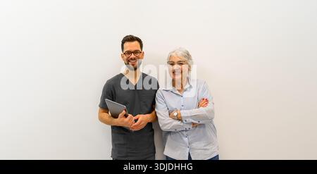 Ritratto dell'oftalmologo maschile sorridente con paziente anziano in piedi insieme su sfondo bianco Foto Stock
