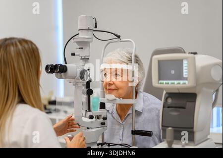 Oftalmologo donna che esegue l'esame oculistico su donna anziana con lampada a fessura durante la valutazione della vista presso la clinica Foto Stock