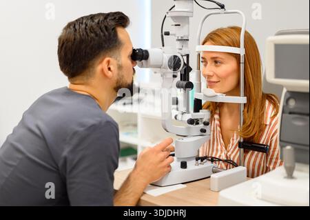 Oftalmologo maschile che esegue un esame oculare con lampada a fessura su paziente durante il check-up presso la moderna clinica di cura della vista Foto Stock