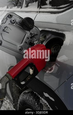 Primo piano di un ugello del carburante inserito nel serbatoio del carburante di un'auto in una stazione di rifornimento. Rifornimento di carburante presso la stazione di rifornimento, ugello della pompa di alimentazione all'interno del serbatoio del gas Foto Stock