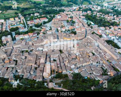 Vista aerea dei tetti in terracotta e degli edifici baciati dal sole raggruppati intorno a Piazza del popolo, San Severino Marche, Italia. Foto Stock