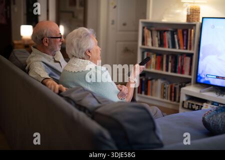 Bella coppia di anziani che guardava la televisione la sera. Foto Stock