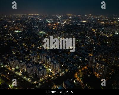 Vista aerea di un vasto paesaggio urbano illuminato da innumerevoli luci, che proietta un caldo bagliore sul paesaggio urbano, Gurugram, Haryana, India. Foto Stock
