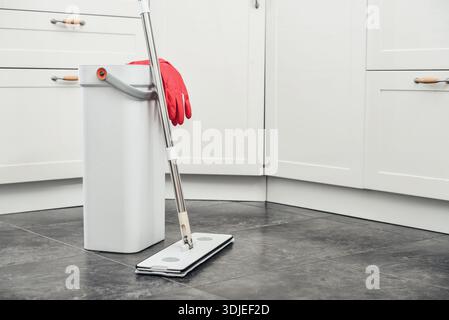 Prodotti per la pulizia: Mocio, secchio con strizzatore seduto su pavimento piastrellato in cucina moderna, utensili per attrezzature umide, concetto di pulizia. Enfatizzando Home sanit Foto Stock