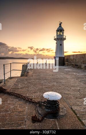 Alba sul faro sulle mura del porto a Mevagissey, Cornovaglia Foto Stock